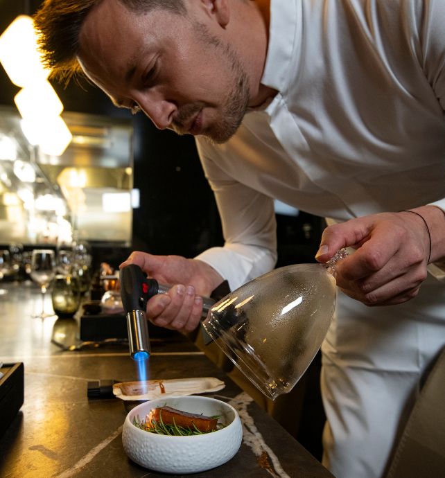 Chef Tom Goetter using a flame torch on a dish