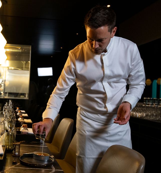 Chef Tom Goetter pouring sauce on a dish