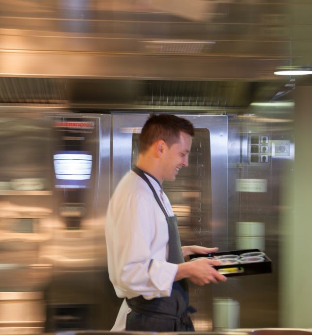 Chef Tom Goetter carrying a tray in the kitchen